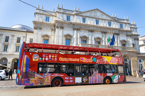 Open Tour double decker bus  with tourists near La Scala theatre in Milan, Italy