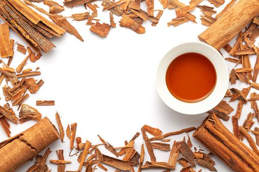 Top view wallpaper of Dry organic Cinnamon sticks (Cinnamomum verum), along with its essential oil.  Isolated on a white background.