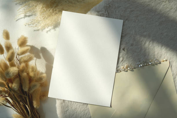 istock Top view mockup blank card, for greeting, wedding invitation template with grass flower on earthy neutral colors cloth background. 1936802117