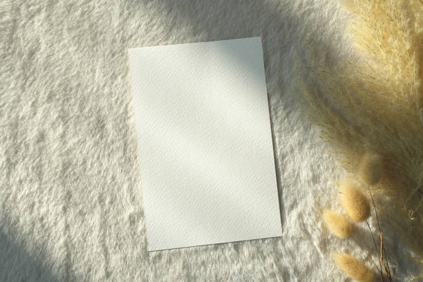 istock Top view mockup blank card, for greeting, wedding invitation template with grass flower on earthy neutral colors cloth background. 1936802120
