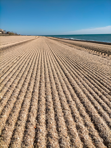 Vilassar de Mar-Barcelona beach, first thing in the morning in summer, freshly brushed with the tractor.
Horizontal lines are observed that disappear along the beach, blue sky and the Mediterranean Sea on the right hand side. photo