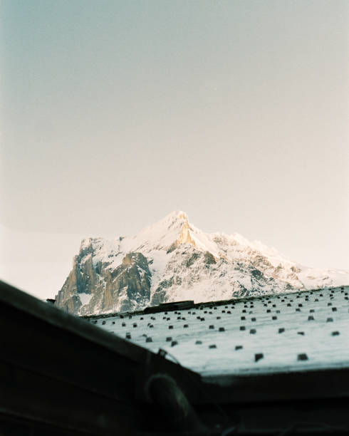 Jungfrau peak showing above a traditional Swiss roodtop as the morning sun kisses the mountain