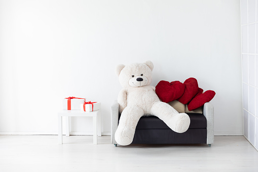 Two small teddy bears sitting on a sofa with Christmas presents