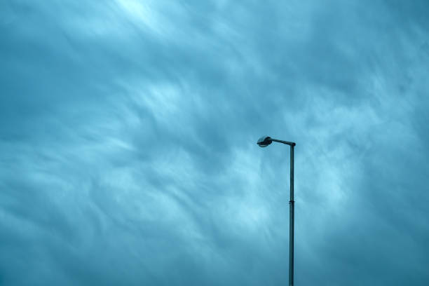 Street light lamp on a tall post against moody dramatic sky, minimalistic composition