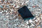 Lost smart phone device in pebbles on seaside beach in summer morning