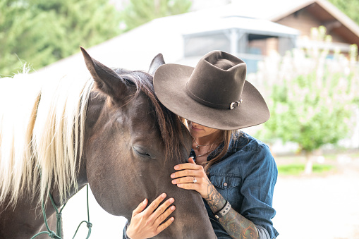 Rancher woman strokes horses muzzle at ranch