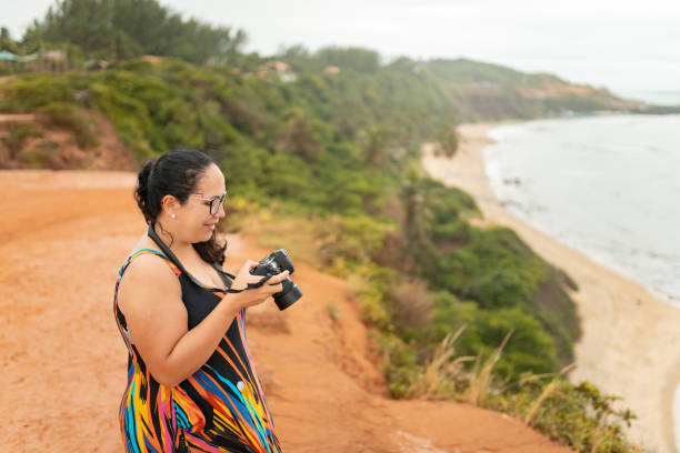 istock Tourist with camera on cliff on the beach 1936935986