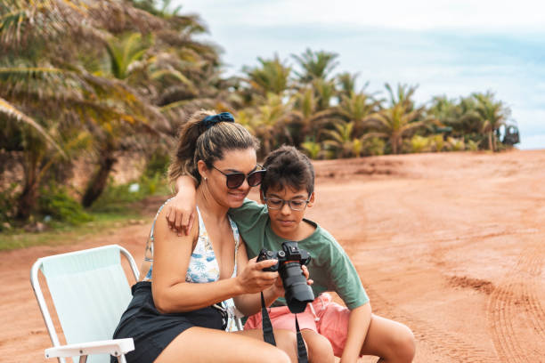 istock Mother and son sitting holding camera on the beach 1936936003