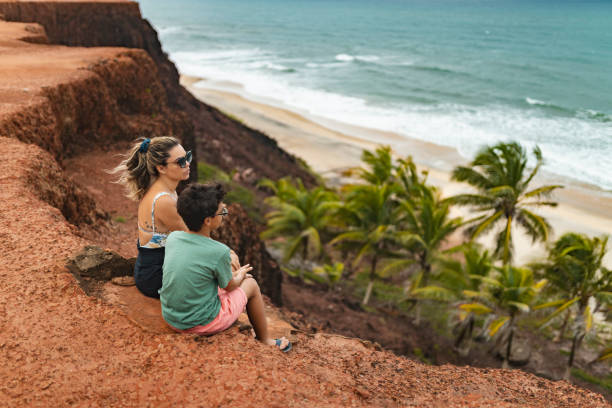 istock Mother and son sitting on cliff at the beach 1936940408