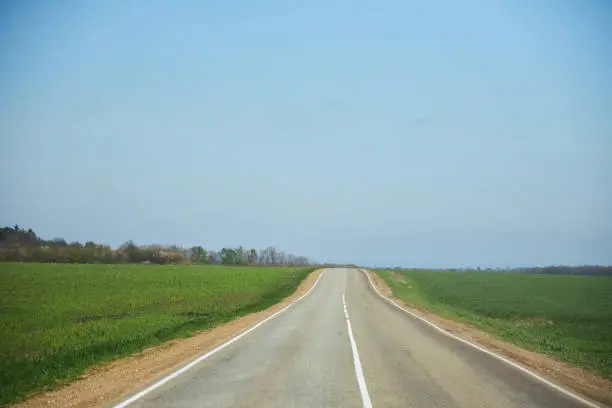 A road without settlements, stretching into the distance. The concept of travel and long-distance travel.