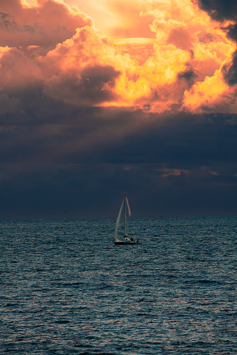 a boat taking hte sea while the sunset pierce through the burning sky