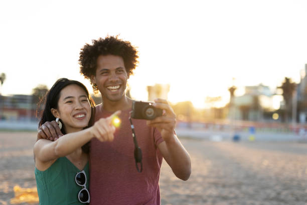 istock Beautiful young couple taking photos at the beach 1936976607