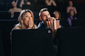 Couple watching a scary movie at cinema.