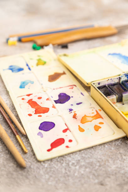 istock Drawing accessories set: brushes, pencils, watercolor on brown concrete. Side view, selective focus 1937017553