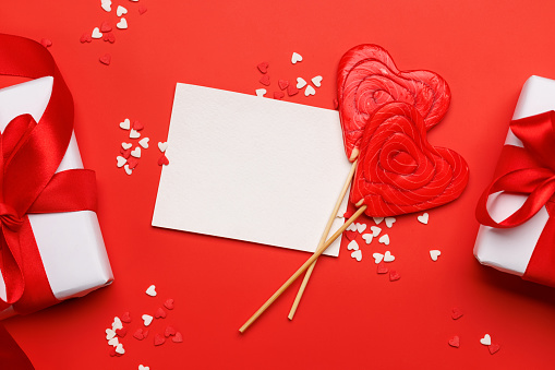 Heart lollipops: Sweet treats on a red backdrop with text space. Flat lay Valentines day card