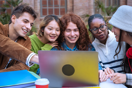 Group of multiracial students, meeting on university campus, working together on creative tasks, preparing for university exams, using laptop. Education, study of university life concept.