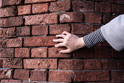 person touching brick wall