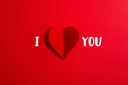I Love You phrase and red heart shaped textile on red background
