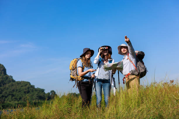 istock trekking family backpacker standing holding compass and map, while the other person pointing finger and using binoculars to look at view, 1937045793