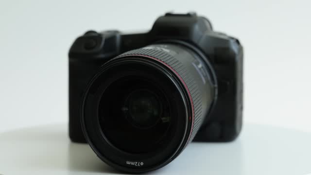 Black photo camera with lens rotating on white background closeup