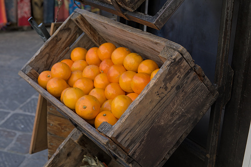 Lots of oranges in an old suspended wooden crate on a market stall.