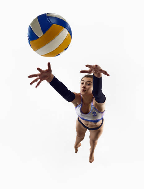 istock Top view. Dynamic image of athletic female volleyball player in motion, practicing, jumping with ball isolated over white studio background. 1937077630