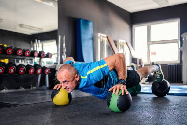 istock Confident man using medicine ball while doing push-up exercises in gym 1937078208