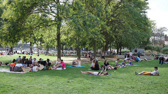 Paris, France - July 16, 2017: Lot of people enjoying day and relaxing on grass in one of many city parks