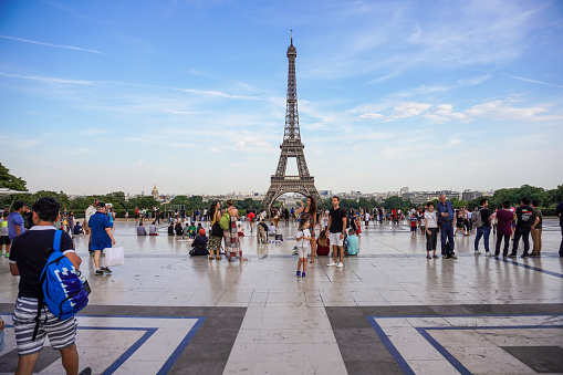 Paris, France - July 18, 2017: Lot of people enjoying day and relaxing on Trocadero square and garden with Eiffel Tower in background. Sunny evening just before sunset.