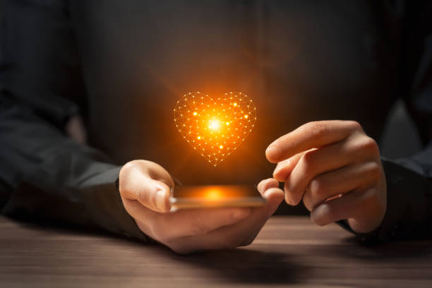 istock Futuristic love concept with hand holding smartphone with glowing AI heart 1937092165