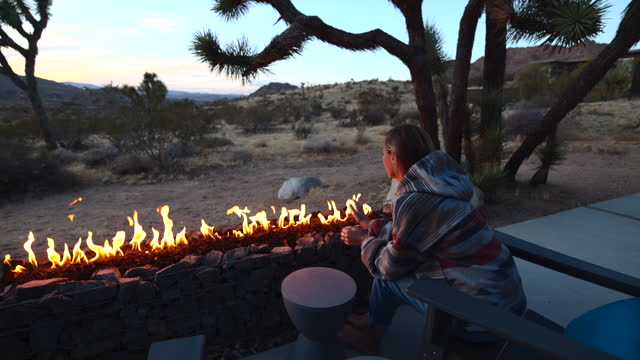 Carefree woman relaxing by the fire pit on a cool winter night in the desert, luxury travel