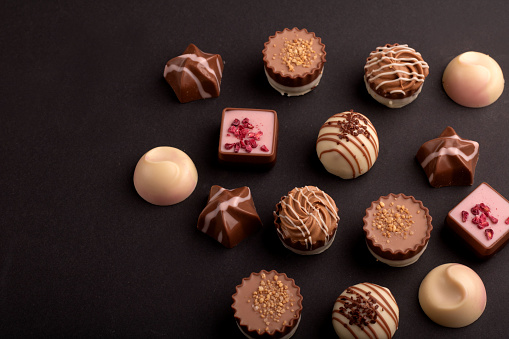 A tempting photo of a chocolate truffle assortment. This delicious candy and dessert selection, against a background, promises a tasty and sweet indulgencemaking it an ideal gift for those who appreciate a flavorful treat. calorie, sweet food