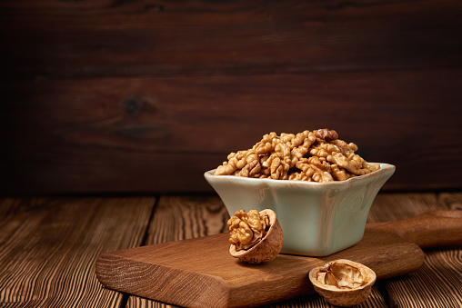 A bowl of peeled walnut kernels on a rustic background with copy space. Low angle view.