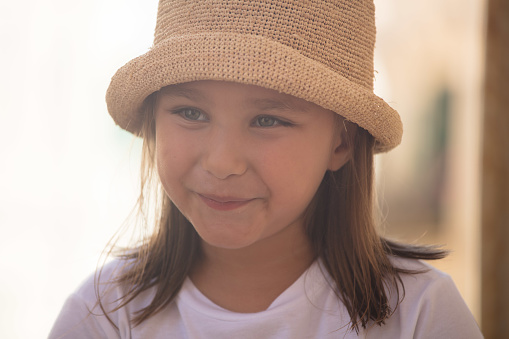 She wears a straw hat and she jokingly smiles with her mouth and eyes.