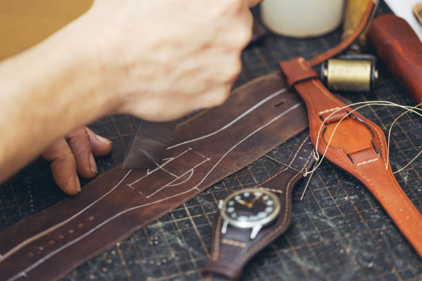 istock Close up of a shoemaker or artisan worker hands. Leather craft tools on old wood table. 1937122282
