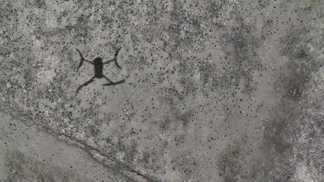 Shadow of drone landing on concrete floor