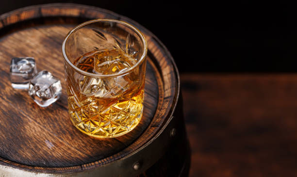 istock Whiskey glass with ice on a rustic barrel, a classic sip 1937126209