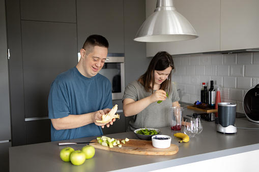 Carefree couple with special needs preparing healthy smoothie in the kitchen.