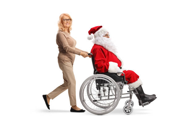 middle aged woman pushing santa claus in a wheelchair - physical injury men orthopedic equipment isolated on white imagens e fotografias de stock