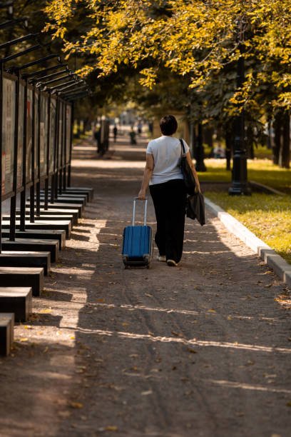 istock A middle-aged woman walks along the boulevard with a suitcase 1937136806