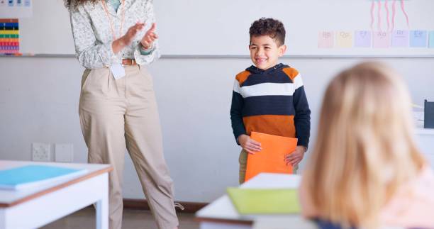istock Class, presentation and child speaker with applause and cheering in classroom at school. Young kid, education and oral reading of project with a student and teacher with children group in discussion 1937157454
