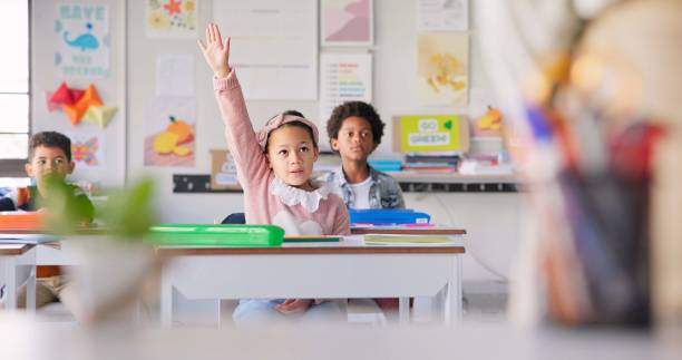 istock Education, question and students with girl in classroom for learning, discussion and knowledge. Help, studying and future with children and hands raised at school for why, scholarship and answer 1937157978