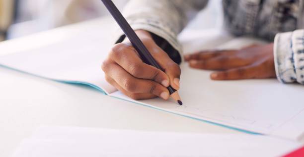 istock Hands, kid and writing in book, classroom and learning with development, language or paper at desk. Child, scholarship and education with notebook, pen and studying at academy, school or kindergarten 1937158013