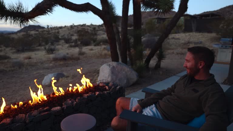 Carefree man relaxing by the fire pit on a cool winter night in the desert, luxury travel