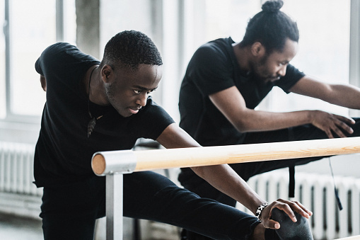 Black men stretching and warming up in dance studio before training