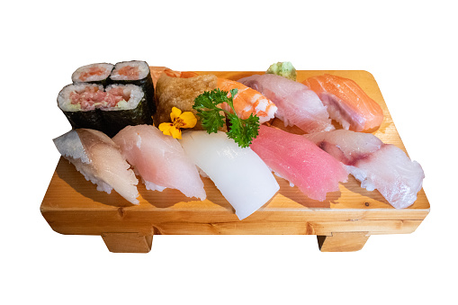 Set of various kinds and types of Japanese food sushi fish ready to eat on a wooden tray on a white background.