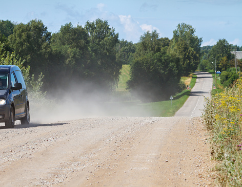 A car on a dusty gravel road.