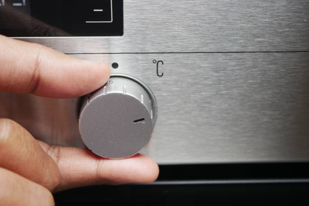 istock Close up of men hand setting temperature control on oven. 1937195193