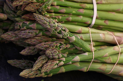 Bunch of fresh green asparagus shoots at retail market display, close up, high angle view