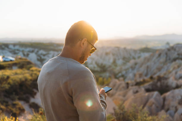 istock Man Traveler Contemplating Scenic Sunset and Using Smartphone in Cappadocia 1937237978